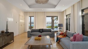 Uma sala de estar ampla, com um sofá cinzento, uma mesa de centro de madeira e um candelabro.
