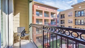 A balcony with a metal railing, a small table, and a chair. - MD Anderson Med Center  Free Parking (Houston)