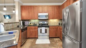 A modern kitchen with wooden cabinets, stainless steel appliances, and a tiled backsplash. - MD Anderson Med Center  Free Parking (Houston)