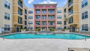 A multi-story building with a central courtyard featuring a swimming pool and a fountain. - MD Anderson Med Center  Free Parking (Houston)