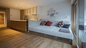 A modern living room with a sofa, a coffee table, and a kitchen area with wooden cabinets and a countertop. - Our Second Home (Kranjska Gora)