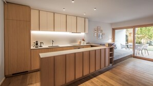 A modern kitchen with wooden cabinets, a central island, and a large sliding glass door leading to an outdoor patio area. - Our Second Home (Kranjska Gora)