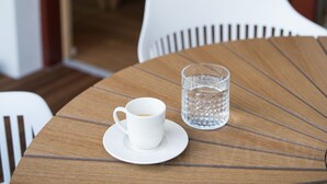 A dining table with a white cup and glass, a wooden floor, and a dining area in the background. - Our Second Home (Kranjska Gora)