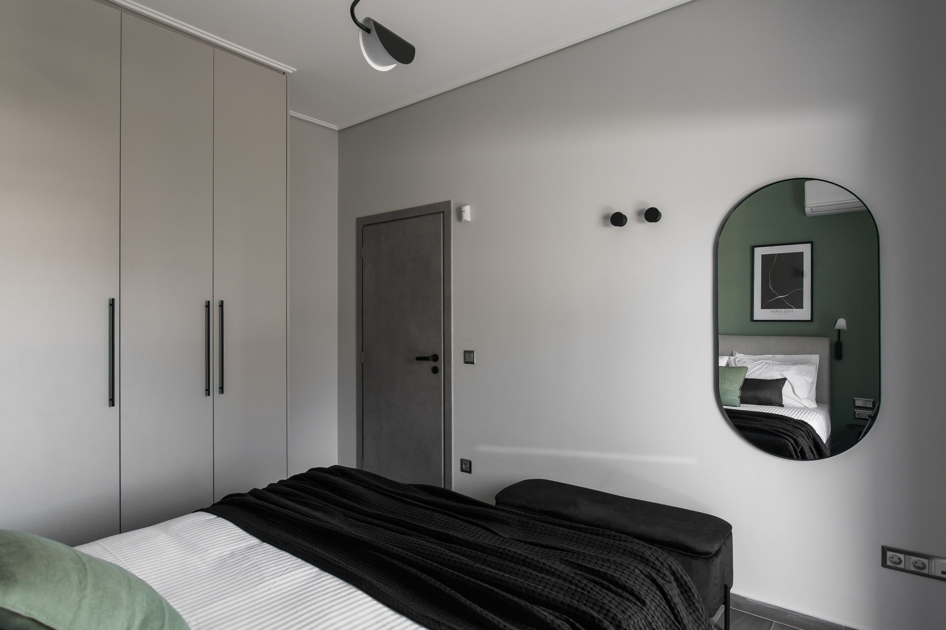 A bedroom with a bed, a wardrobe, a door, a mirror, and a light fixture.