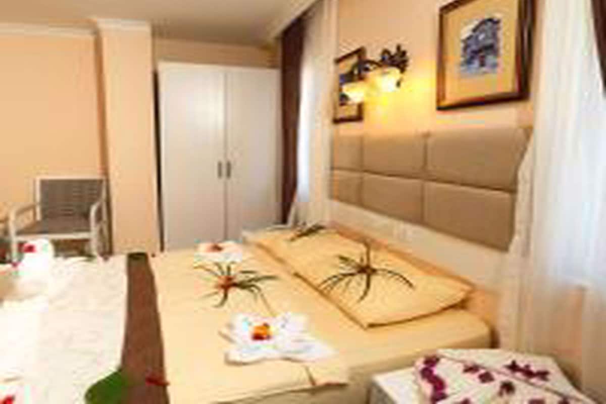 A hotel room with a bed, a chair, a wardrobe, and a framed picture on the wall.