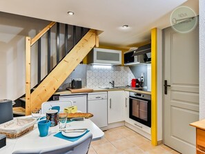 A compact kitchen with a wooden staircase, white cabinets, a microwave, and a stove.