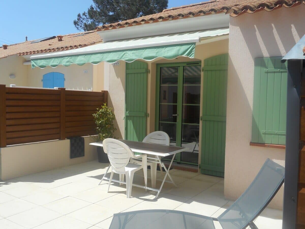Eine Terrasse mit Tisch und Stühlen, ein Holzzaun und eine grüne Tür.