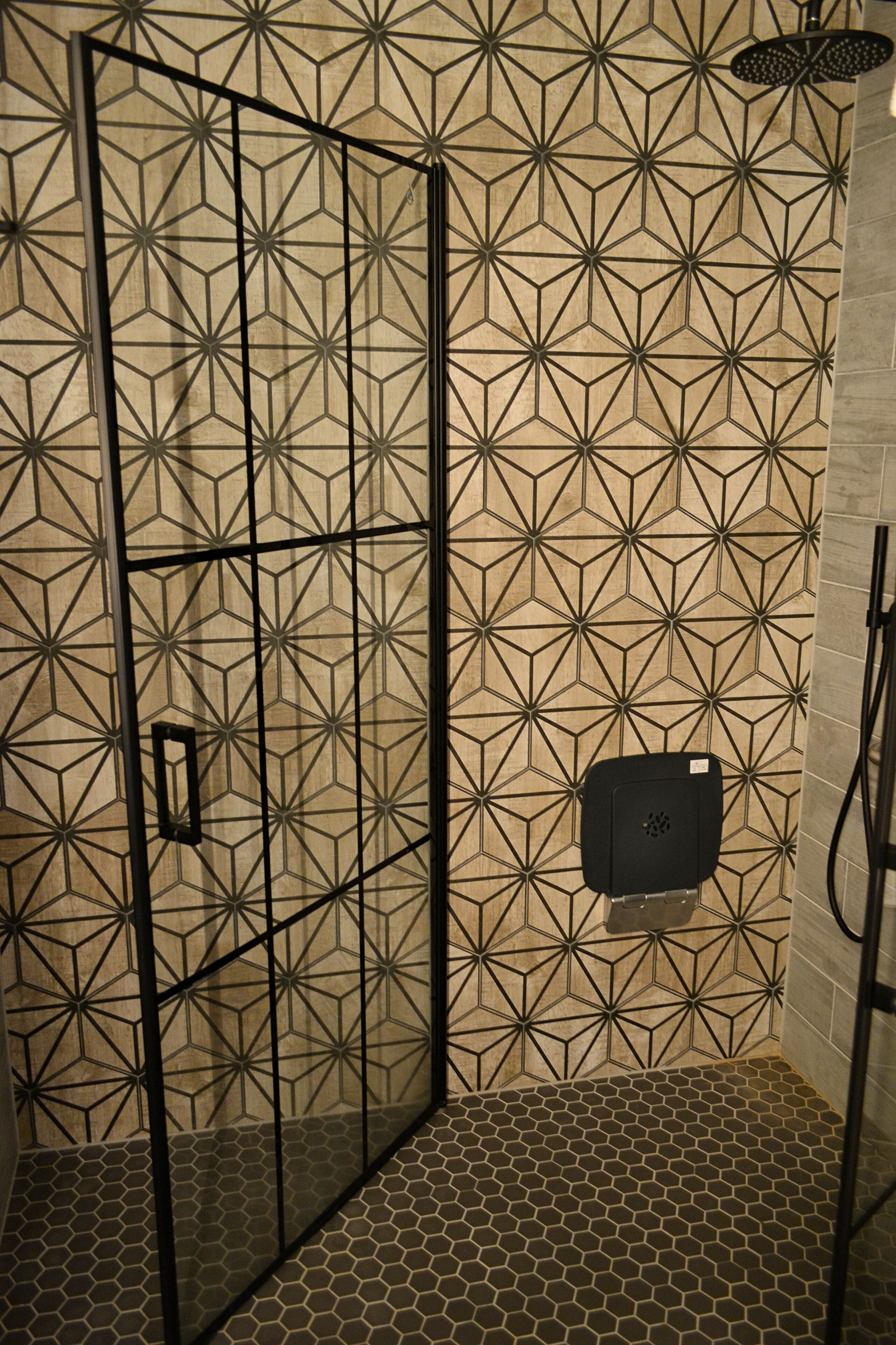 Zona de ducha con un diseño geométrico en los azulejos de las paredes y el suelo.