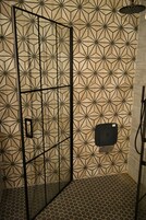 Zona de ducha con un diseño geométrico en los azulejos de las paredes y el suelo.