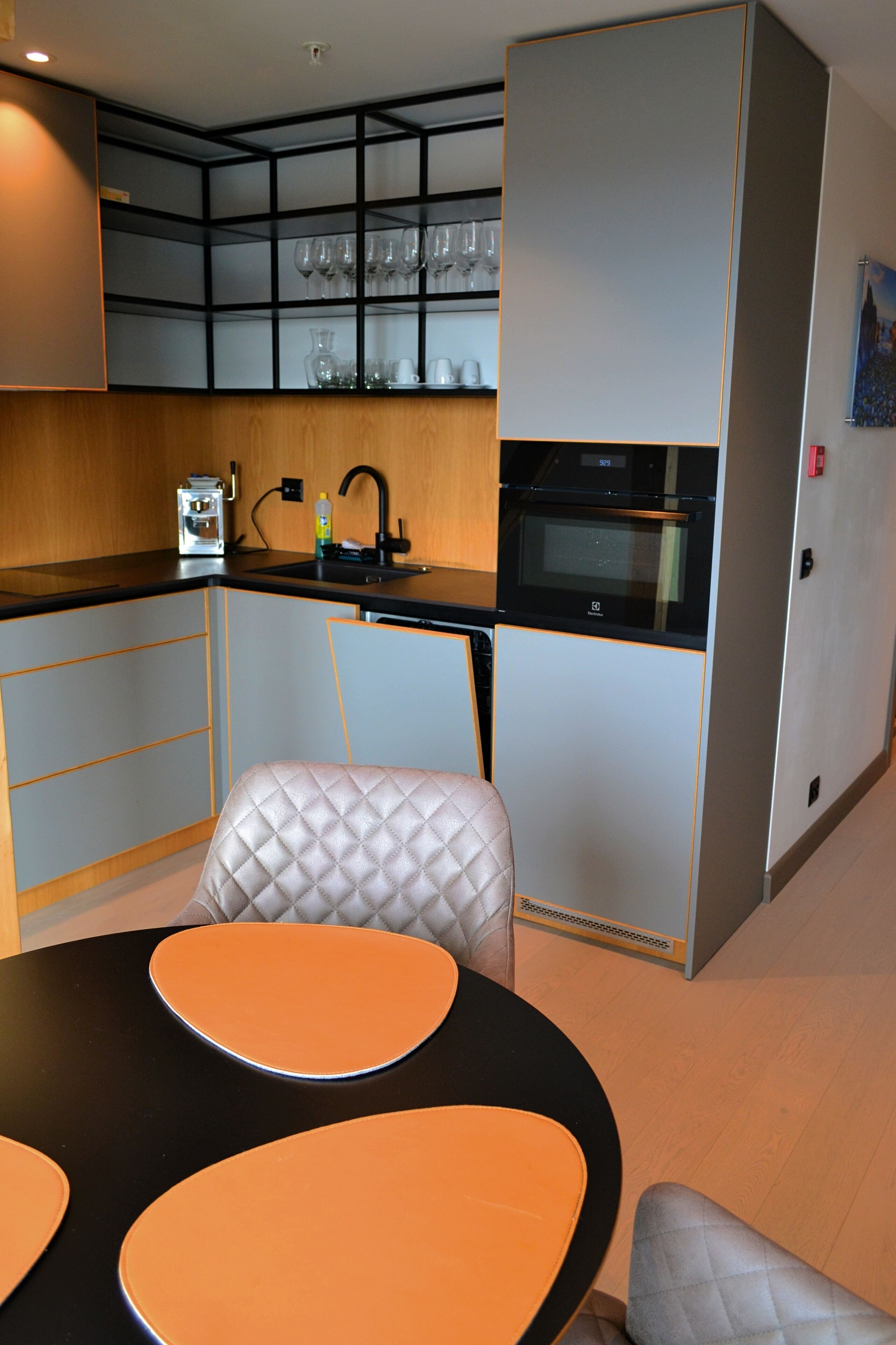 Cocina compacta con horno integrado, lavamanos y encimera. Hay un comedor con mesa y sillas.