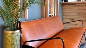 Een modern interieur met een leren bank, een plant in pot en houten planken met groen.
