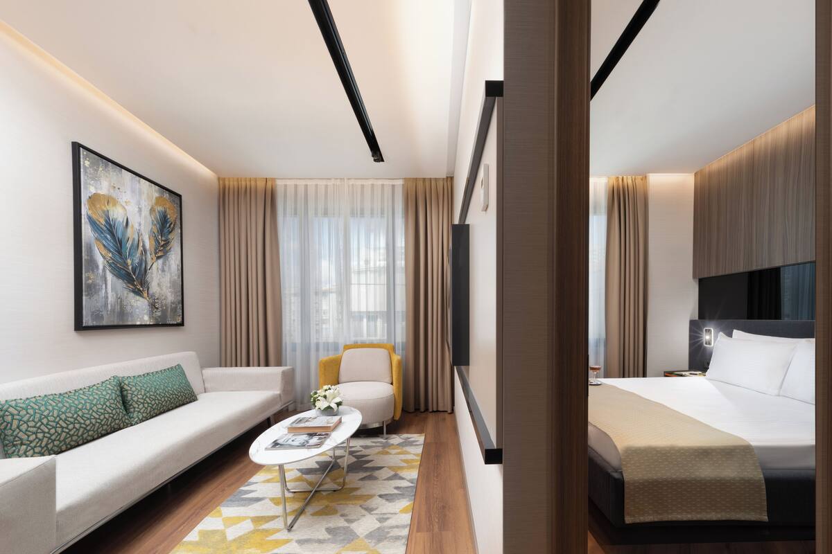 Una habitación de hotel moderna con sofá, una mesita de centro, cama y sillón.