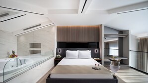 A modern hotel room with a large bed, a glass-enclosed bathroom, and a view of the city. - Nish Palace Besiktas (Istanbul)