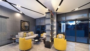 A modern living room with a sofa, yellow armchairs, a coffee table, and a decorative wall piece. - Nish Palace Besiktas (Istanbul)