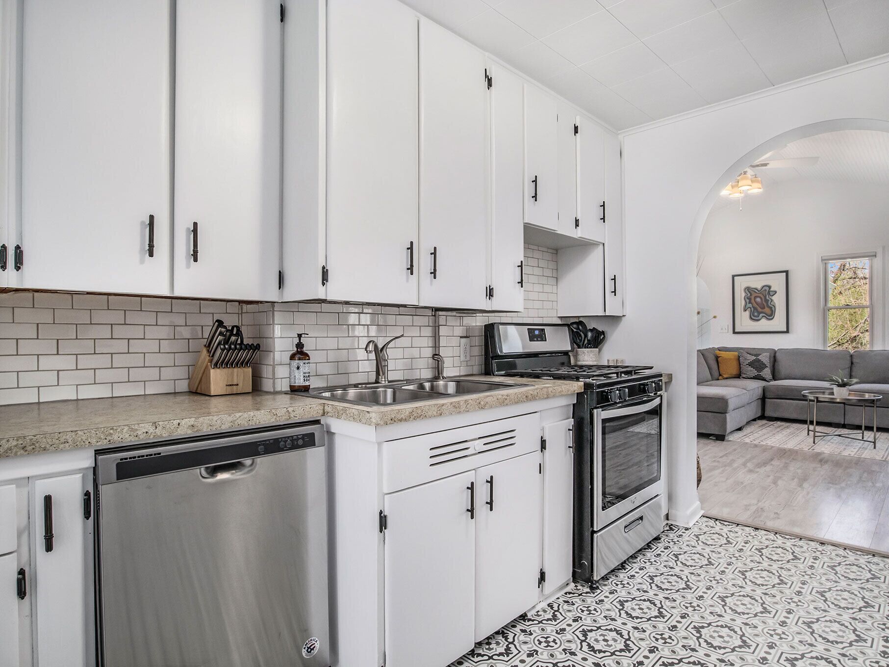 Una cocina moderna con armarios blancos, lavavajillas de acero inoxidable y horno empotrado.