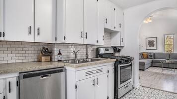 Una cocina moderna con armarios blancos, lavavajillas de acero inoxidable y horno empotrado.
