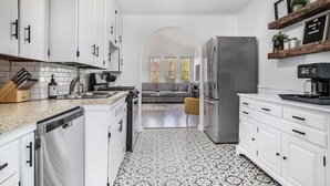 Una cocina moderna con armarios blancos, un refrigerador de acero inoxidable y un suelo con diseño.