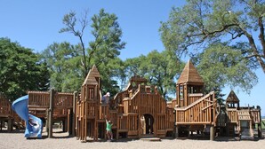Una estructura de madera para jugar con varias zonas de escalada y un tobogán.