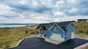 A two-story house with a garage, a driveway, and a view of a lake.