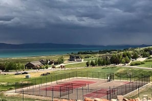 A residential area with houses, a basketball court, and a view of a large body of water under a cloudy sky. - Unobstructed Lake Views! Bunk Room w/ Video Games! Ping Pong & Foosball! Extra Fridge & Freezer Space! (Fish Haven)