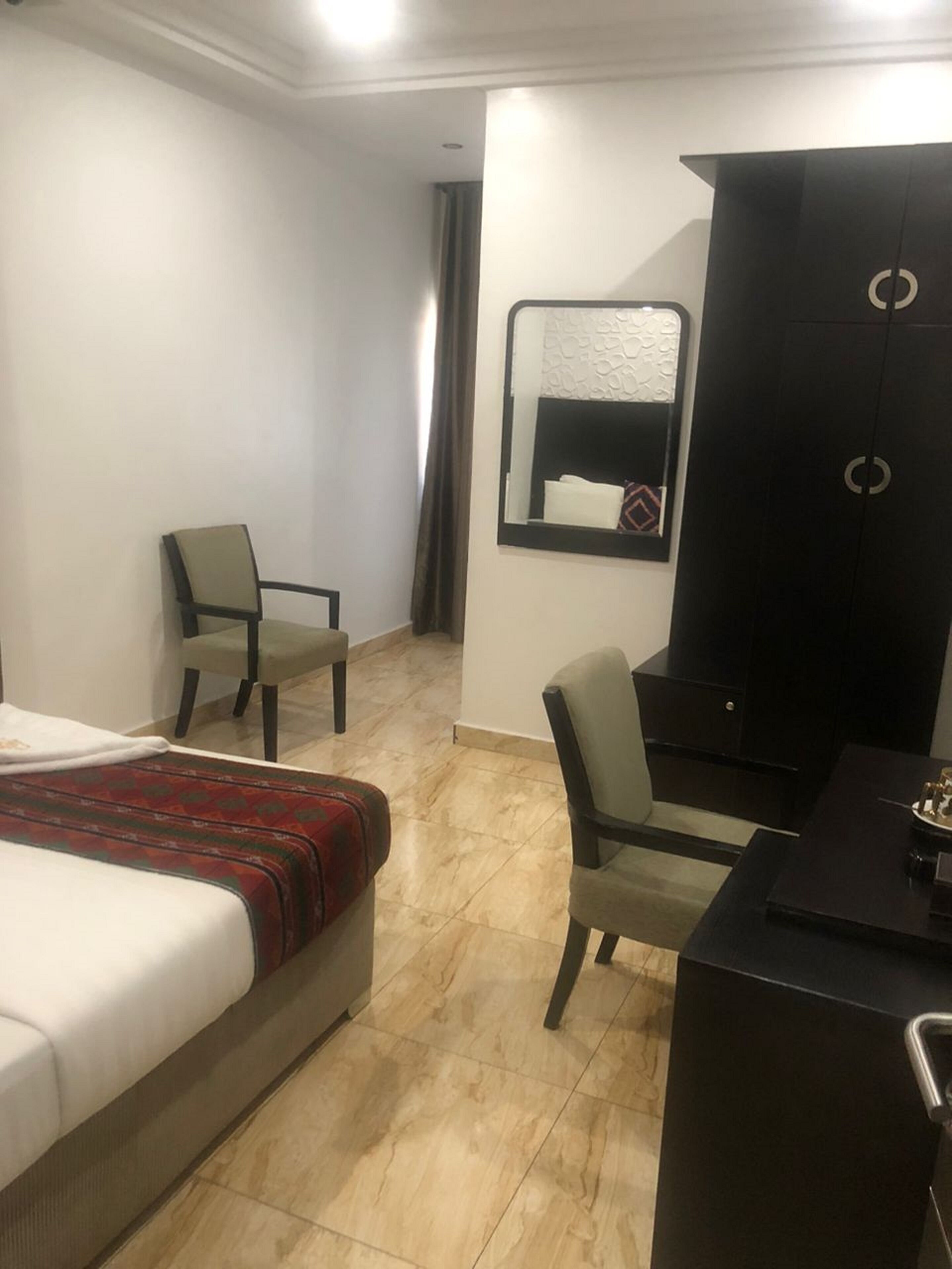 Una camera d'albergo con un letto, una scrivania, una sedia e un armadio.