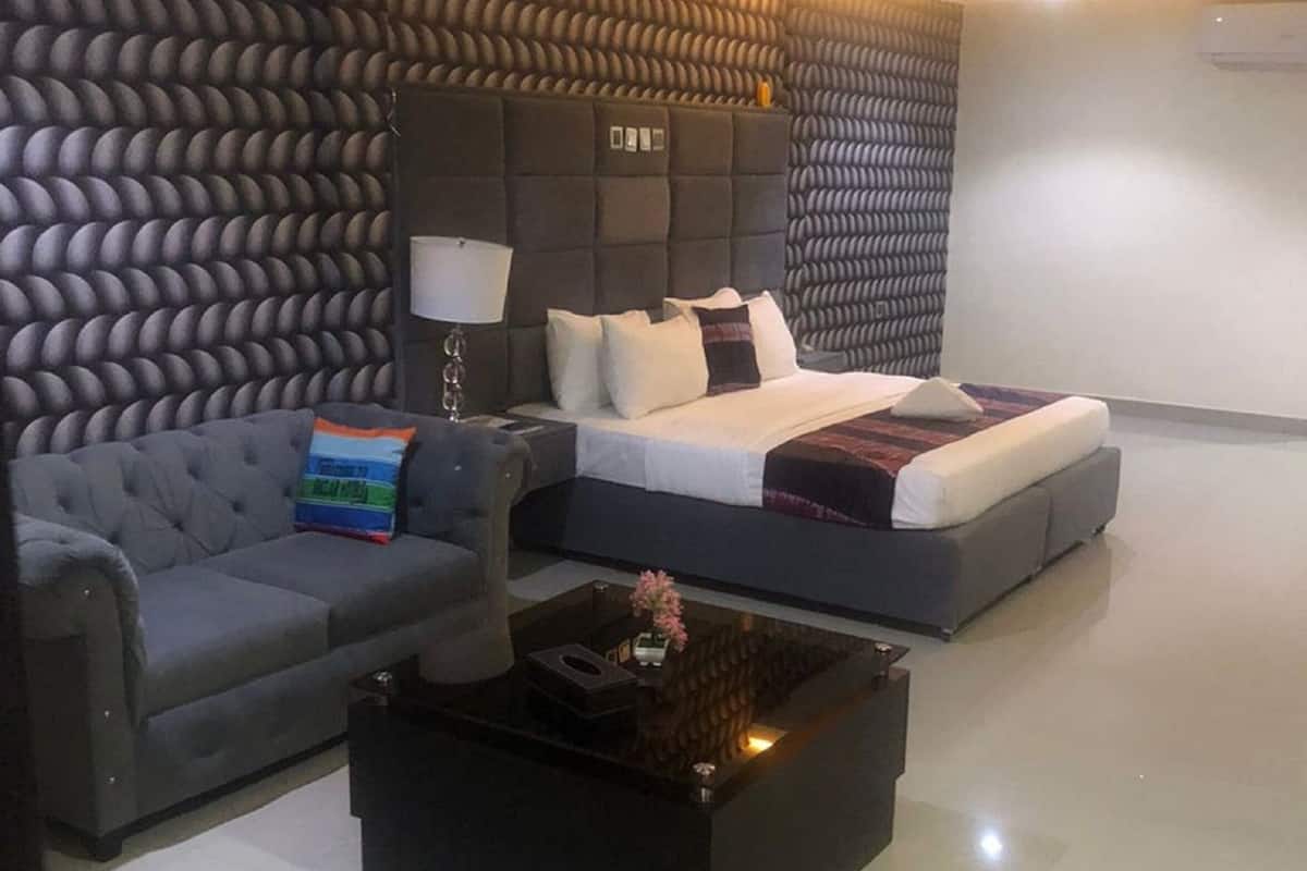 Une chambre d’hôtel moderne, équipée d’un canapé, d’un lit, d’une table basse et d’un mur au revêtement texturé original.