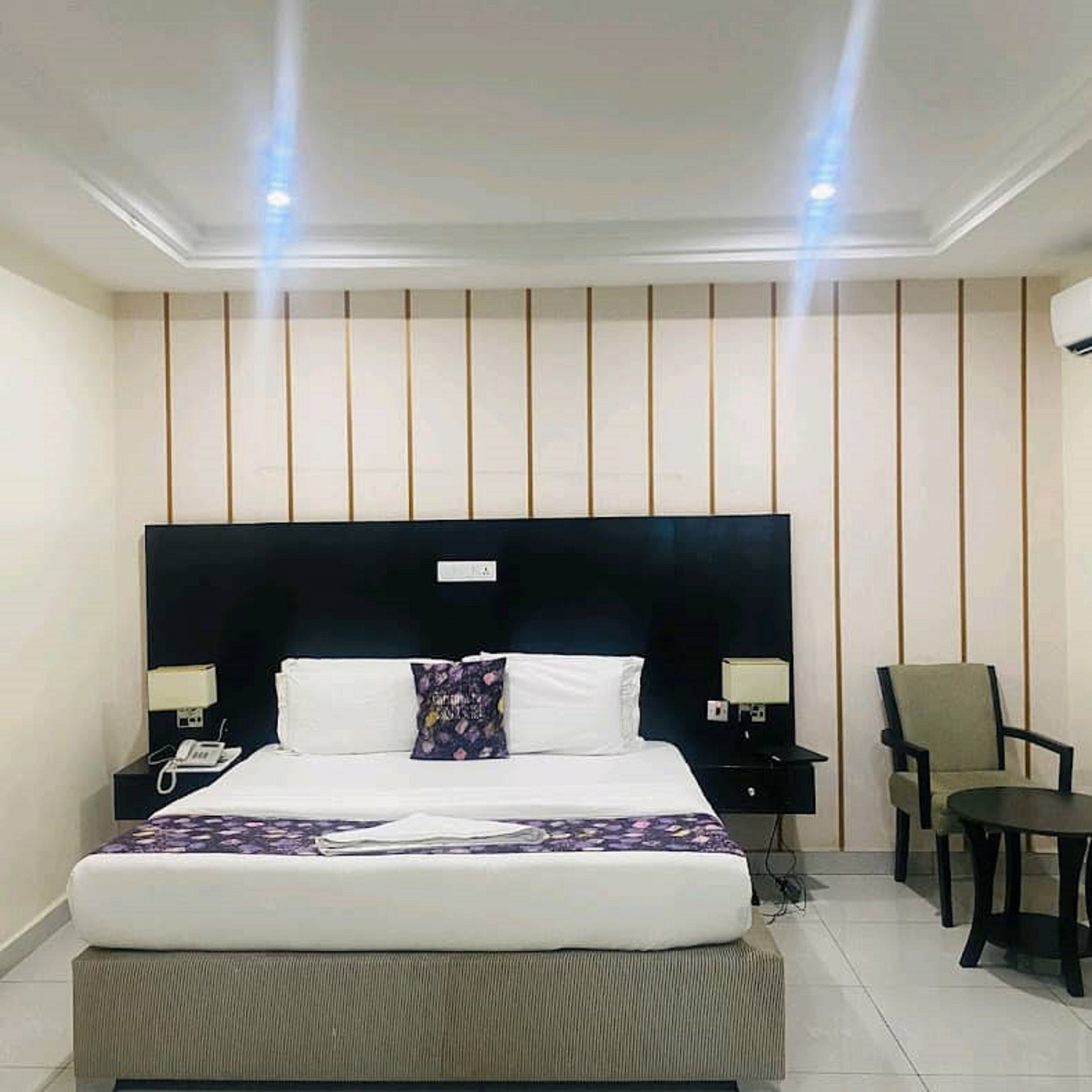 A hotel room with a large bed, two bedside tables, a chair, and a nightstand.