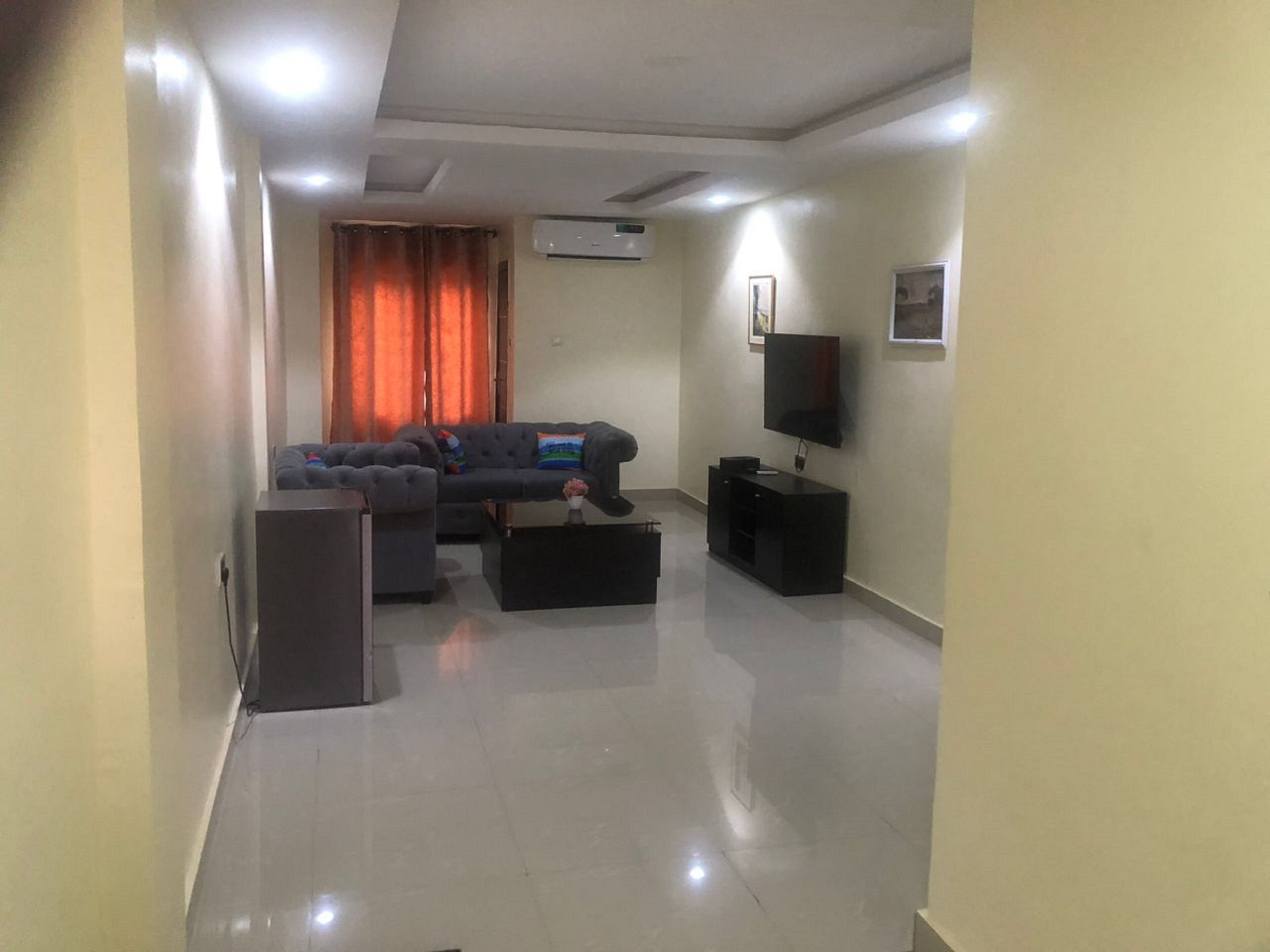 A modern living room with a sectional sofa, a flat-screen TV, and a black entertainment unit.