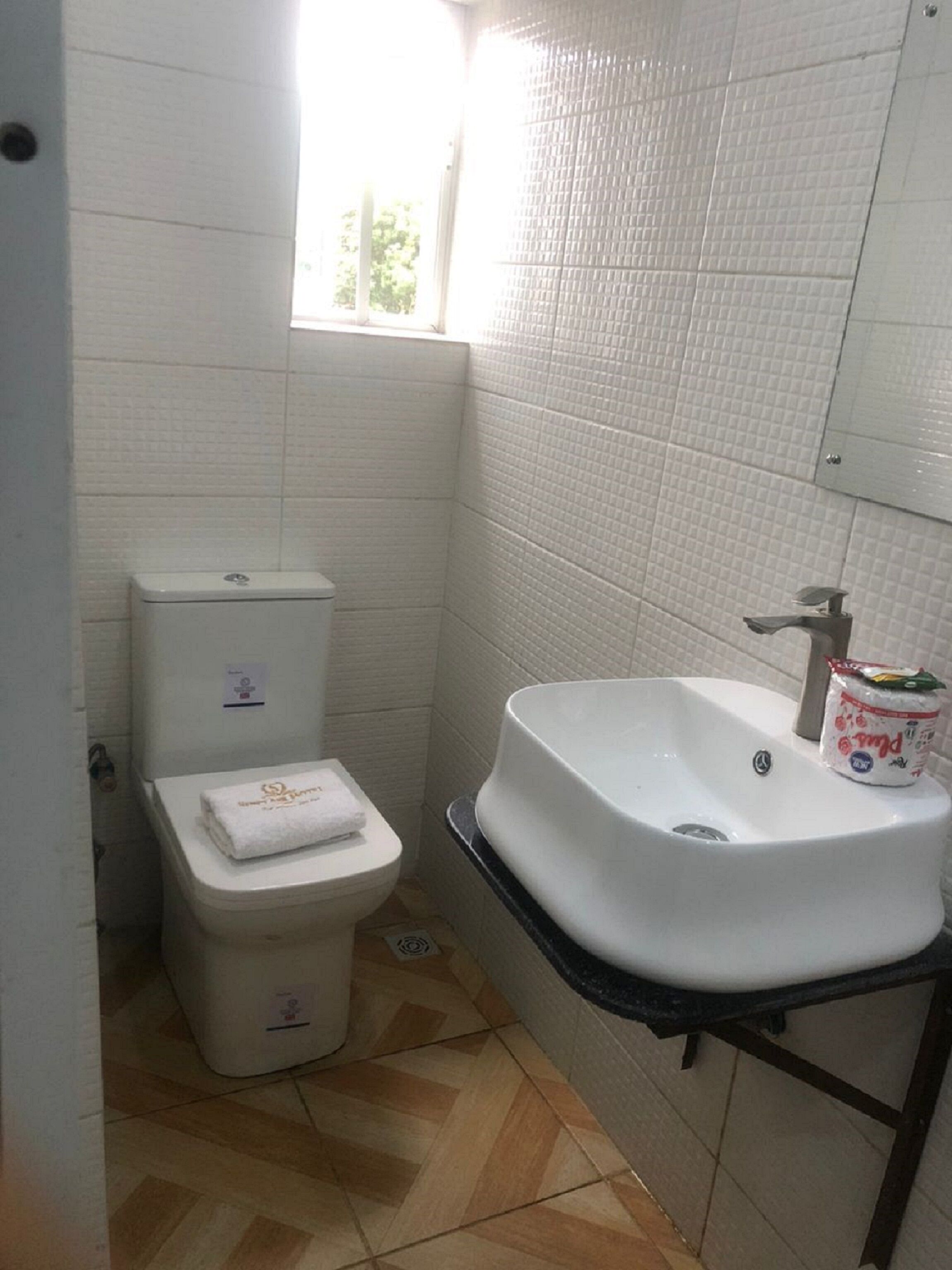 Een kleine badkamer met een toilet, een wastafel en een raam.