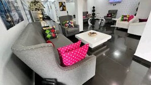 Un salon moderne avec un canapé gris, une table basse blanche et un téléviseur fixé au mur.