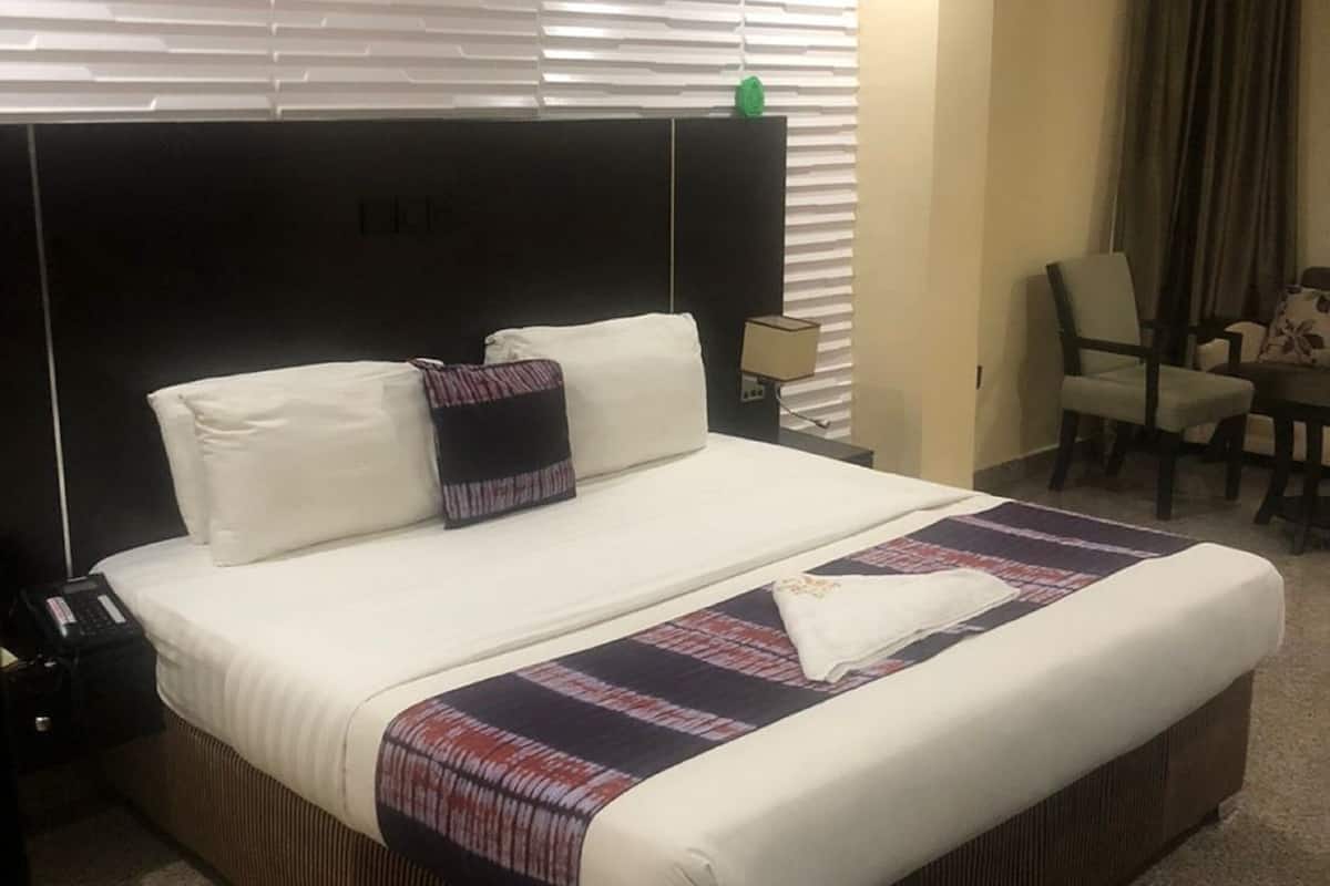 Une chambre d’hôtel avec un grand lit, une table de chevet, une chaise et une petite table.