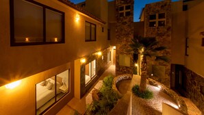 A courtyard with a bed, a small table, and a lamp.