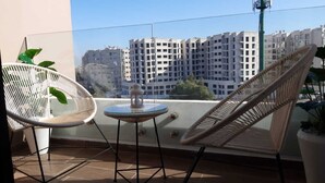 A balcony with two wicker chairs and a small table, overlooking a cityscape with high-rise buildings. - Chez Miguel- Casablanca daily rental with swimming pool (Casablanca)