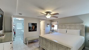 A bedroom with a large bed, a ceiling fan, a bench, a TV, and a painting on the wall. - Sangria Dreams A | Close Walk to the Beach! (Miramar Beach)