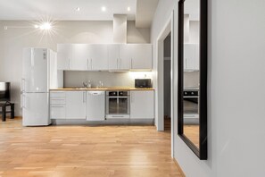 Una cocina moderna con armarios blancos, un microondas, un horno y un refrigerador.