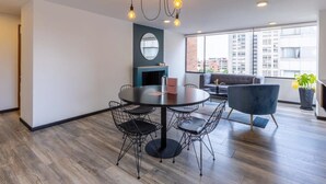 Un interior moderno con una mesa de comedor redonda, sillas de estructura de alambre negra y un sillón azul.