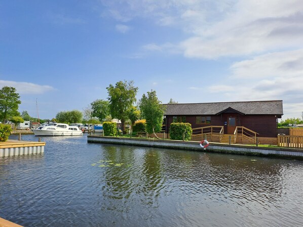 A riverside dock with boats, a wooden building, and a clear sky.