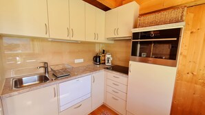 A compact kitchen with white cabinets, a stainless steel sink, a built-in oven, and a coffee maker. - Cozy vacation home, perfect for families - hiking, skiing on the doorstep (Hohentauern)