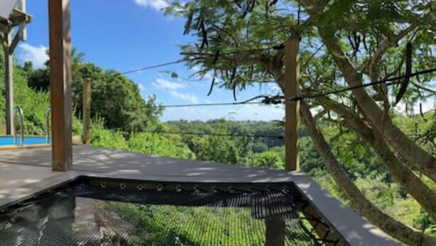 A wooden deck with lounge chairs and a pool, surrounded by lush greenery and trees. - Charming bungalow & private pool (Le Gosier, Guadeloupe)