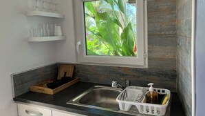 A compact kitchen with a window, a sink, and a countertop. - Charming bungalow & private pool (Le Gosier, Guadeloupe)