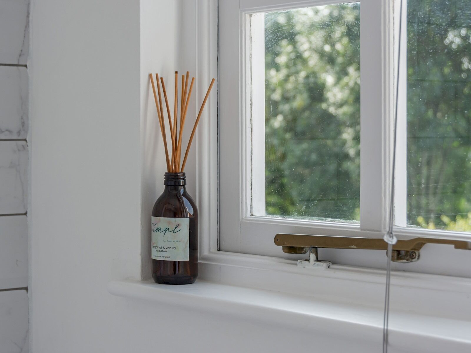 A bottle of reed diffuser with a label on a windowsill.