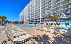 Un hotel con una amplia zona de piscina, varios balcones y tumbonas.
