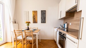 A modern kitchen with wooden cabinets, a built-in oven, and a dining area with a table and chairs.
