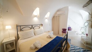 Un dormitorio con cama, mesita de noche, lámpara y vistas al baño.