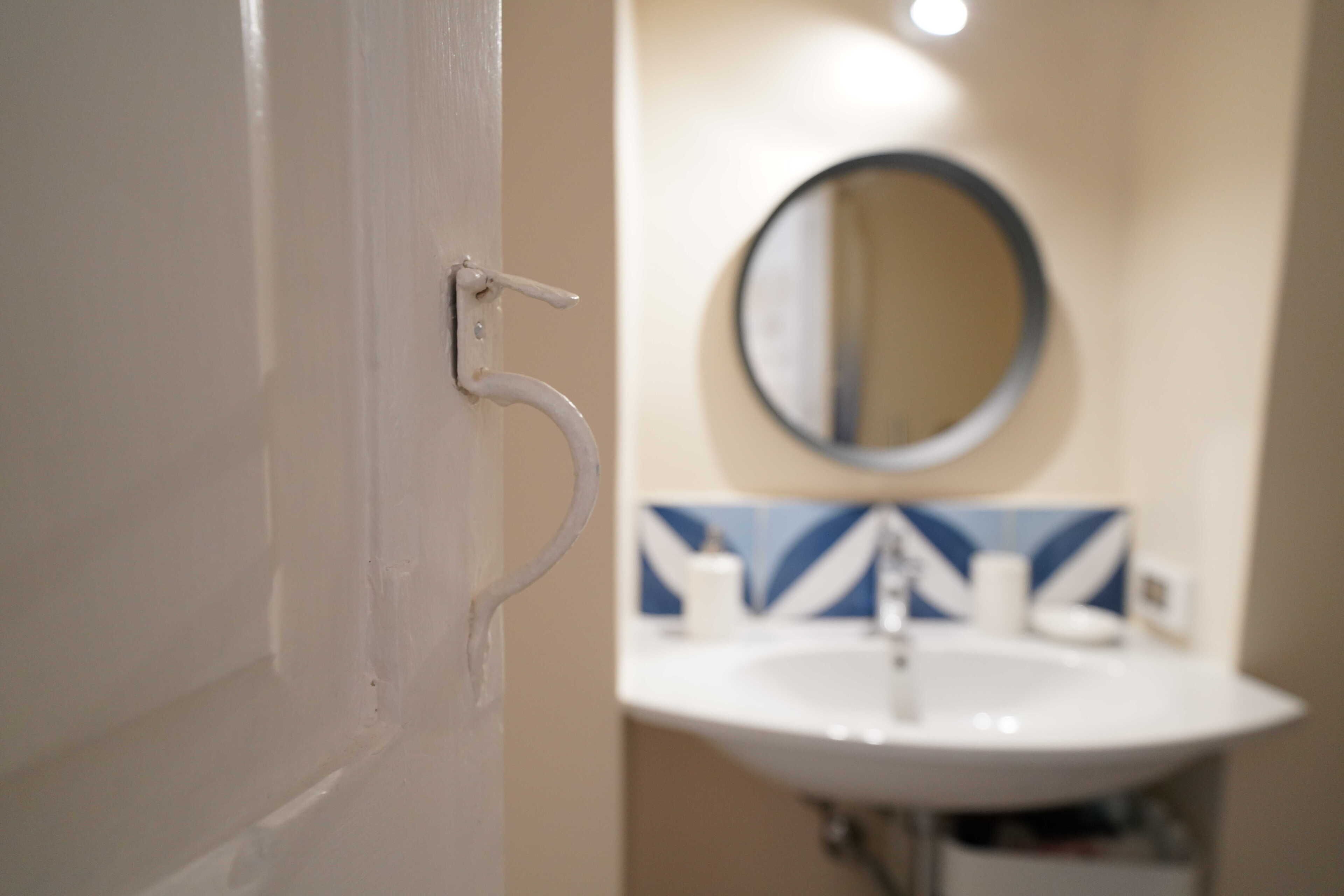 A bathroom with a white sink, a mirror, and a blue and white tiled backsplash.