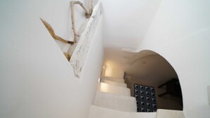 Una escalera con paredes blancas y un muro con diseño geométrico al fondo.
