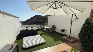 Terraza en la azotea con una mesa, sillas, un jacuzzi y una sombrilla.
