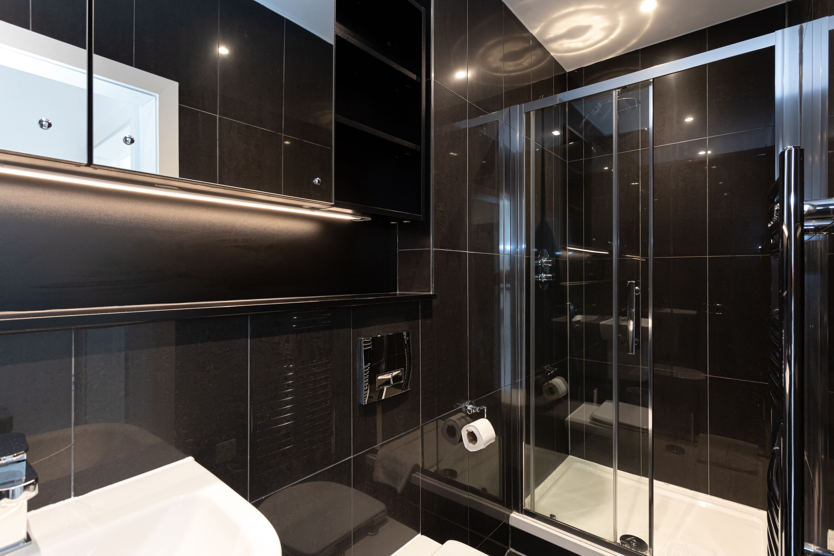 A modern bathroom with a glass shower enclosure, a white sink, and a mirror above the sink.