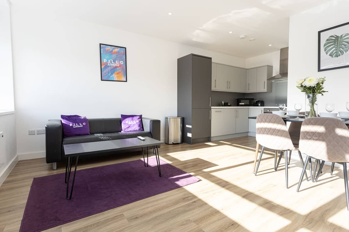 A modern living room with a sofa, coffee table, and a dining area with chairs.