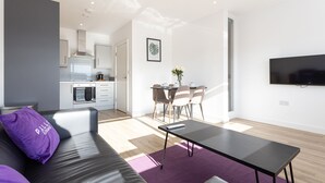 A modern living space with a sofa, a dining table, and a kitchen in the background. - Pillo Rooms Apartments- Manchester Arena (Manchester)